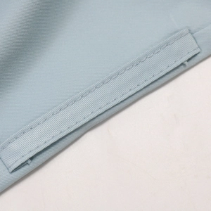 Macro shot of light blue sequin dress fabric with precise stitching and woven texture