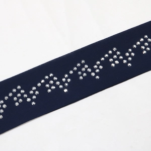 Close-up of zigzag pattern white rhinestones on navy blue chiffon garment trim