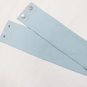 Close-up of light blue fabric belt detail with silver metal snap fasteners on a dress
