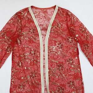 Détail de la robe en tulle rouge avec des motifs floraux en paillettes dorées et galons