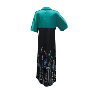 Detail view of smooth green and black satin long dress with floral print on the back hem