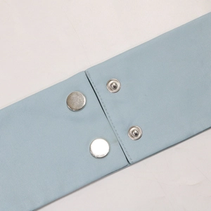 Detail of light blue fabric belt featuring adjustable silver metal snap buttons close-up