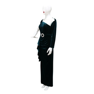 Detail of velvet dress showing emerald green fabric texture and sparkling rhinestone buckle
