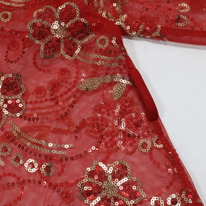 Détail macro du tissu en maille rouge avec broderie florale à paillettes dorées