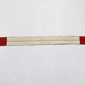 Gros plan du ruban rouge avec broderie de paillettes dorées et motifs géométriques
