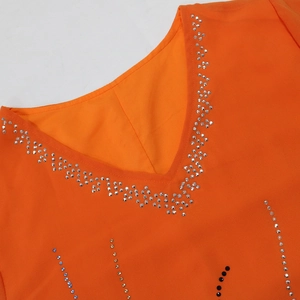 Close-up of sparkling rhinestone patterns on the V-neckline of an orange chiffon dress