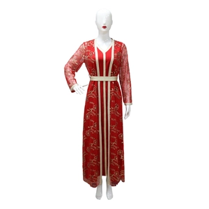 Détail d'un caftan rouge avec broderie florale dorée et finitions en ruban à paillettes