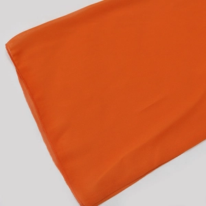 Detailed view of bright orange chiffon dress fabric with high-quality edge stitching