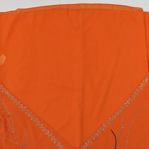 Close-up of sparkling rhinestones in branch pattern on orange chiffon dress fabric