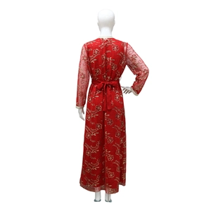 Détail du dos d'une robe rouge à paillettes avec broderies dorées et nœud à la taille