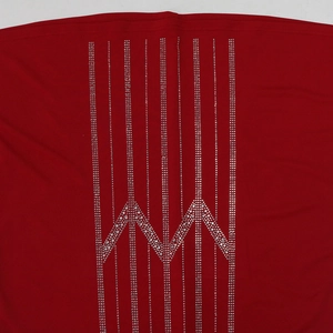 Detailed view of silver rhinestones in geometric M patterns on red knitted fabric