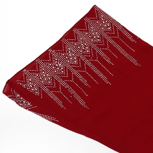 Detailed close-up of wine red chiffon fabric with intricate silver rhinestone ethnic patterns