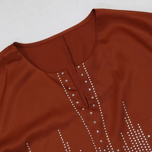 Détail d'une robe en satin rouge avec décolleté en V élégant et bordure en strass brillant