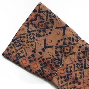 Detailed close-up of ethnic geometric print fabric with refined gold chain trim detailing