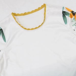 Detail of white robe featuring yellow crochet neckline and floral prints on sleeves