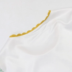 Detailed macro view of yellow scalloped crochet trim on a white silky dress fabric