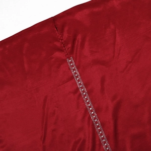 Dettaglio ravvicinato di tessuto satinato rosso scuro con eleganti strass bianchi a due file