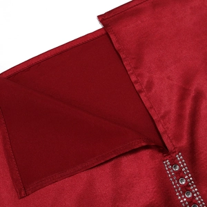 Dettaglio macro del tessuto satinato rosso con strass argento e finiture di cucitura