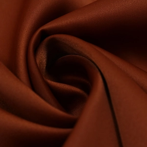Gros plan sur le tissu en satin bronze profond montrant la texture lisse de la robe