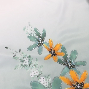 Macro shot of silver rhinestones and floral print detail on mint green fabric