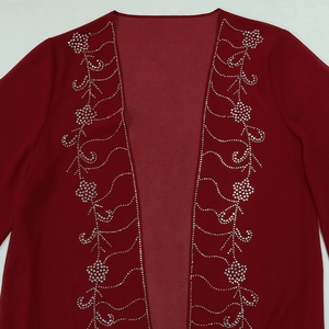 Dettaglio del cardigan in chiffon rosso con eleganti motivi floreali in strass argentati