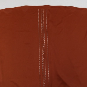Détail de robe de soirée en satin orange avec des chaînes de strass argentés verticaux