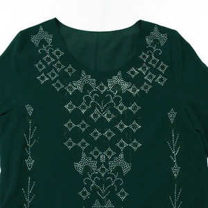 Detail of green chiffon dress featuring symmetric silver and green rhinestone patterns