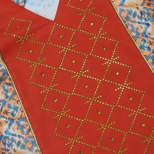 Detail of red V-neck robe with golden trim and sparkling rhinestone geometric patterns