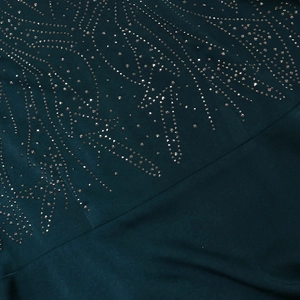 Detail of dark green jalabiya gown with intricate bronze rhinestones in radial patterns