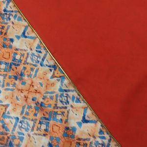 Detailed close-up of ethnic robe fabric with red contrast and gold embroidered piping