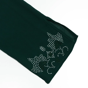 Detailed close-up of dark green robe sleeve featuring silver rhinestone floral patterns