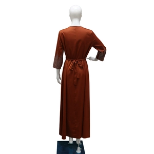 Détail de la robe en satin rouille avec poignets en strass et ceinture à la taille
