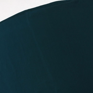 Close-up of deep green jalabiya fabric showing refined texture and precise stitching