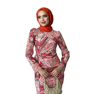Detail of paisley print long-sleeve dress with matching orange hijab and waist tie
