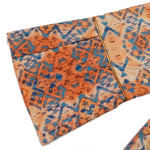 Detail of flared sleeves with ethnic orange and blue patterns and gold cord decoration