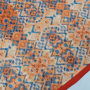 Macro shot of ethnic robe with geometric orange and blue patterns and red edge detail