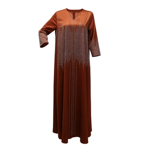 Détail d'un caftan en satin avec motifs en strass et col en V en couleur orange foncé
