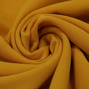 Detailed macro view of mustard yellow chiffon fabric texture with elegant pleated pattern