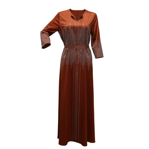 Détail de la robe satinée orange brûlée avec des ornements complexes en strass argentés