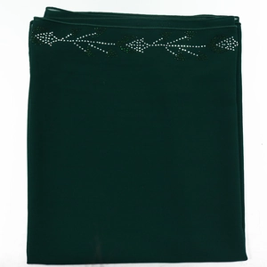 Detailed view of dark green chiffon robe fabric with elegant rhinestone leaf embroidery