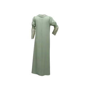 Detail eines hellgrünen Pailletten-Abendkleids, Rückansicht mit eleganten Perlen und Faltenärmeln