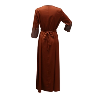 Détail d'une robe de soirée en satin avec des strass sur les manches longues, vue de dos