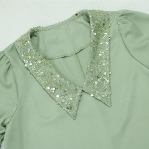 V-Ausschnitt-Detail mit silbernen Pailletten und Perlen auf elegantem mintgrünen Stoff