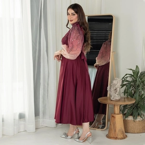 Detail showing the burgundy evening gown featuring sparkling sequins and elegant lantern sleeves