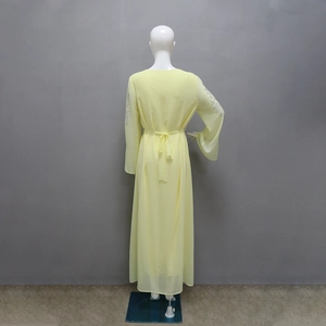 Detail of light yellow chiffon dress featuring rhinestone patterns on sleeves and waist bow