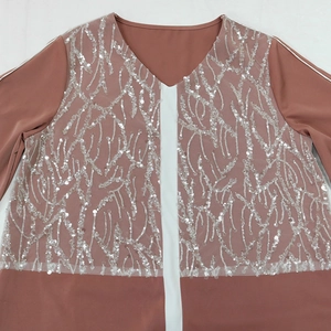 Detailed view of branch-shaped silver sequins and white stitching on a pink satin dress