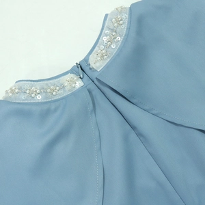 Détail de broderie de fleurs perlées sur décolleté bleu clair avec zip invisible