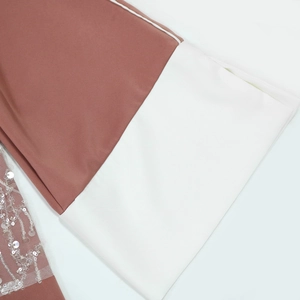 Detail of dusty rose satin fabric with white contrast panels and sequin mesh textures