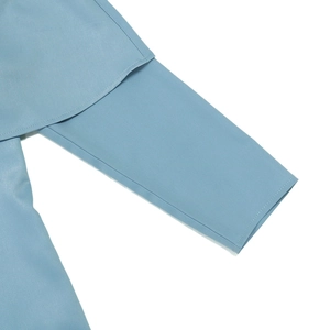 Détail de la robe bleue à manches longues montrant l'épaule superposée et le tissu tissé lisse