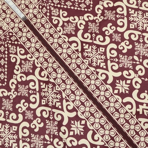 Detailed view of white floral prints and metal zipper on burgundy jalabiya dress fabric